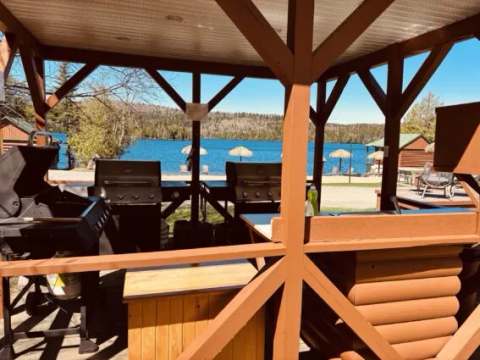 A covered barbecue area offers a direct view of the lake and the beach at Domaine Bazinet.
