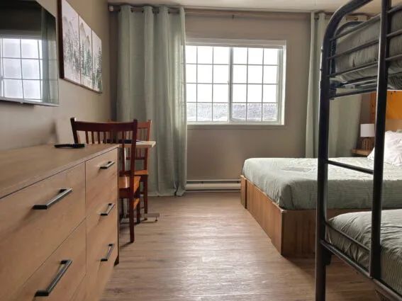 This inn room features a bed, a bunk bed, a dresser, and a workspace.