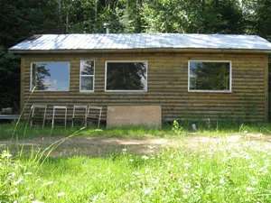 Front view of the Sly cabin featuring log siding and large windows.
