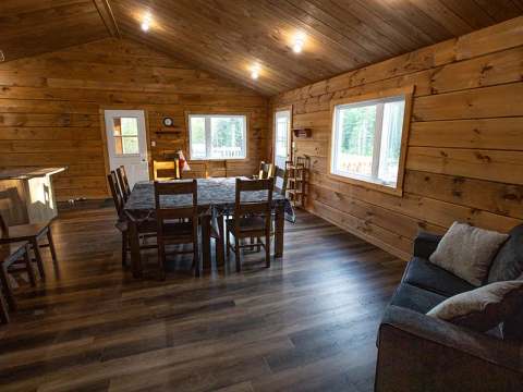The dining room and living room share a warm open space with log walls.
