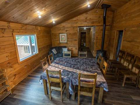 The dining room of the Faucon cabin features a large wooden table with multiple chairs.