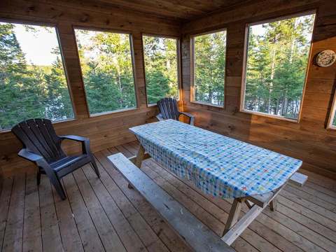 Enjoy a meal with a view of the forest from the enclosed veranda of our Swiss chalet.