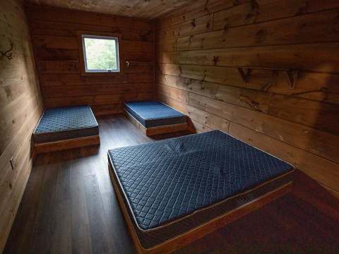 The bedroom in the Faucon cabin is equipped with three single beds on wooden frames.