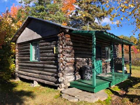 Exterior view of the log cabin surrounded by trees in autumn.