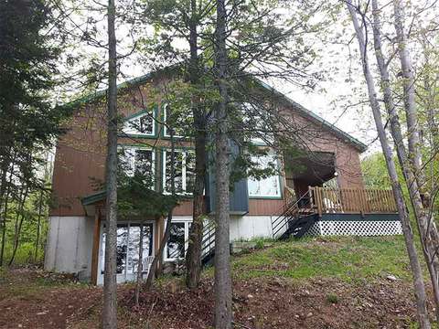 Exterior view of the Le Carcajou cabin nestled by the forest.