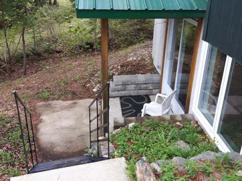 Exterior entrance with concrete stairs leading to the chalet's patio door.