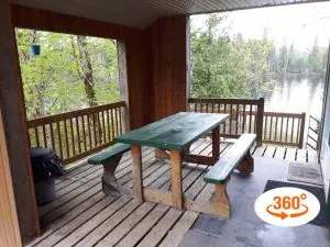The cottage's covered porch offers a picnic table with a view of the lake.