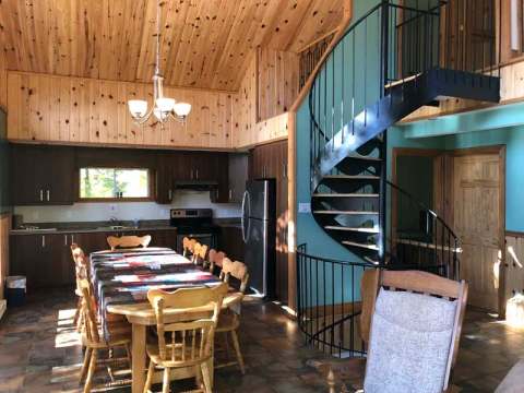 View of the kitchen and dining area with a spiral staircase inside Le Carcajou cottage.