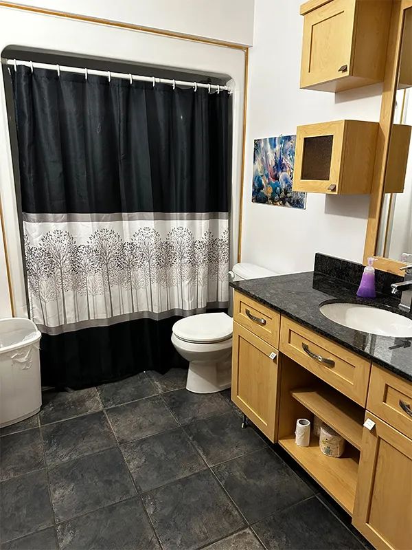 The bathroom at Le Grizzly cabin features a shower with a curtain and a vanity with a sink.