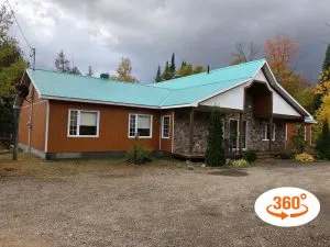 Exterior view of the Le Grizzly cottage with its wooden siding and green roof.