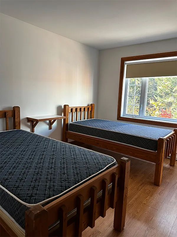 This bedroom at Le Grizzly cottage is equipped with two single beds with wooden frames.