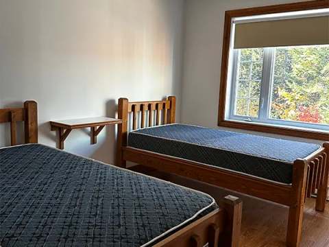 This bedroom at Le Grizzly cottage is equipped with two single beds with wooden frames.