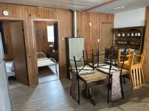Vue de la salle à manger et d'une chambre du chalet Renard avec ses murs en bois.