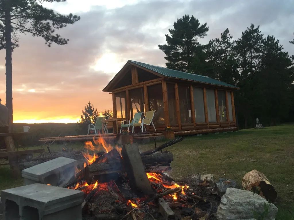 Profitez d'un coucher de soleil inoubliable près d'un feu de camp devant le chalet en bois rond.