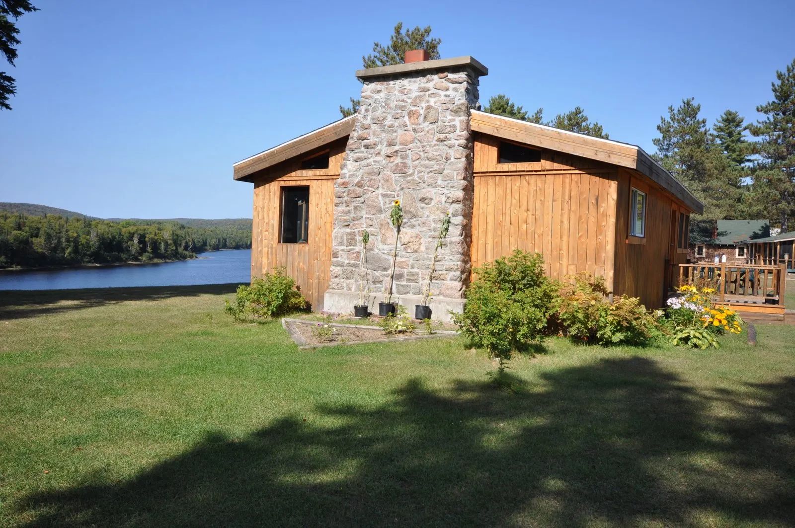 Le chalet en bois avec cheminée en pierre est situé au bord de l'eau.