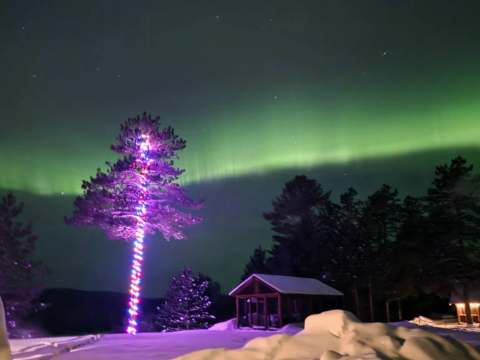 Night view of the chalet under the northern lights in winter.