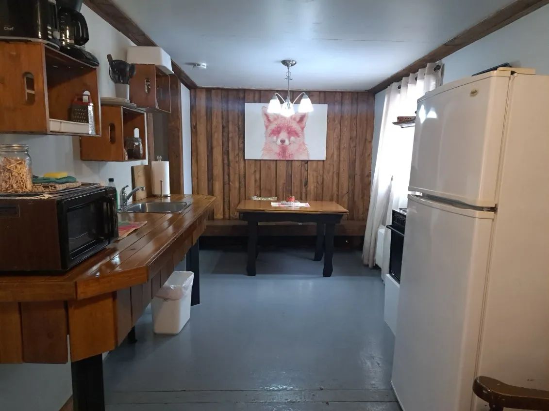 The cottage's functional kitchen is equipped with a refrigerator, a stove, and a dining area.