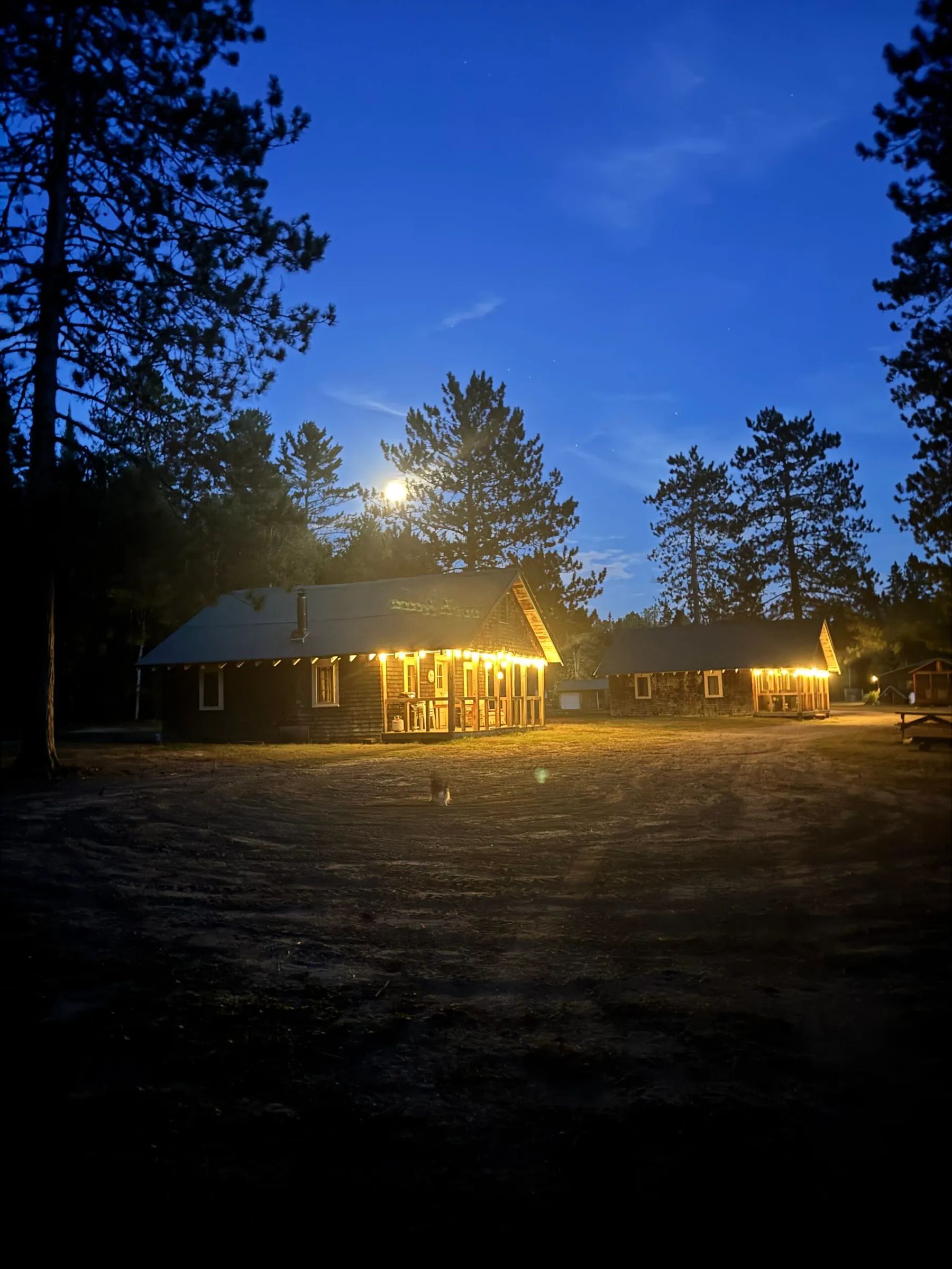 Evening view of the cabins illuminated by string lights.