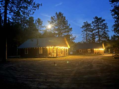 Evening view of the cabins illuminated by string lights.