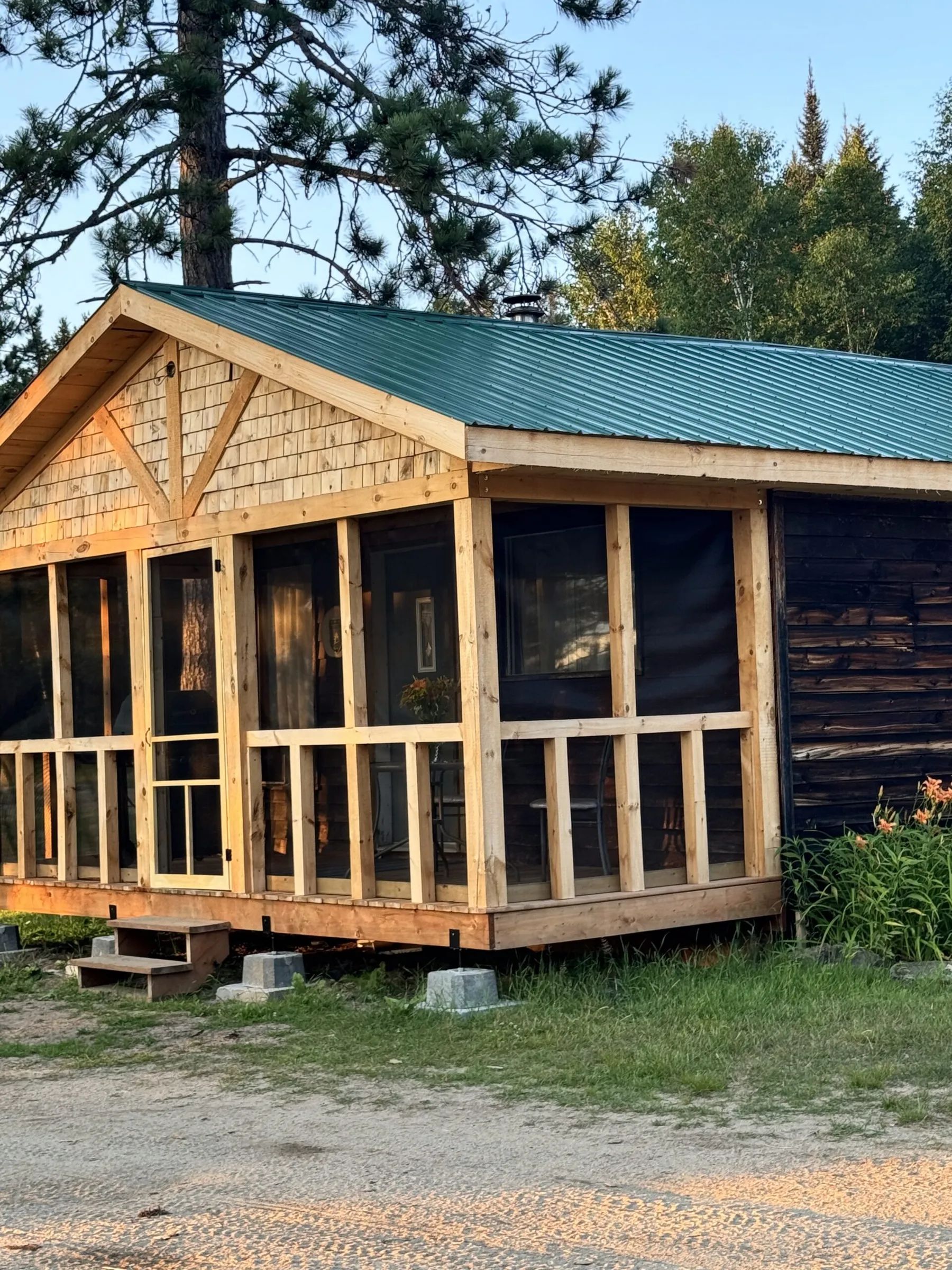 Side view of the L'Aigle cabin featuring its screened porch and green metal roof.