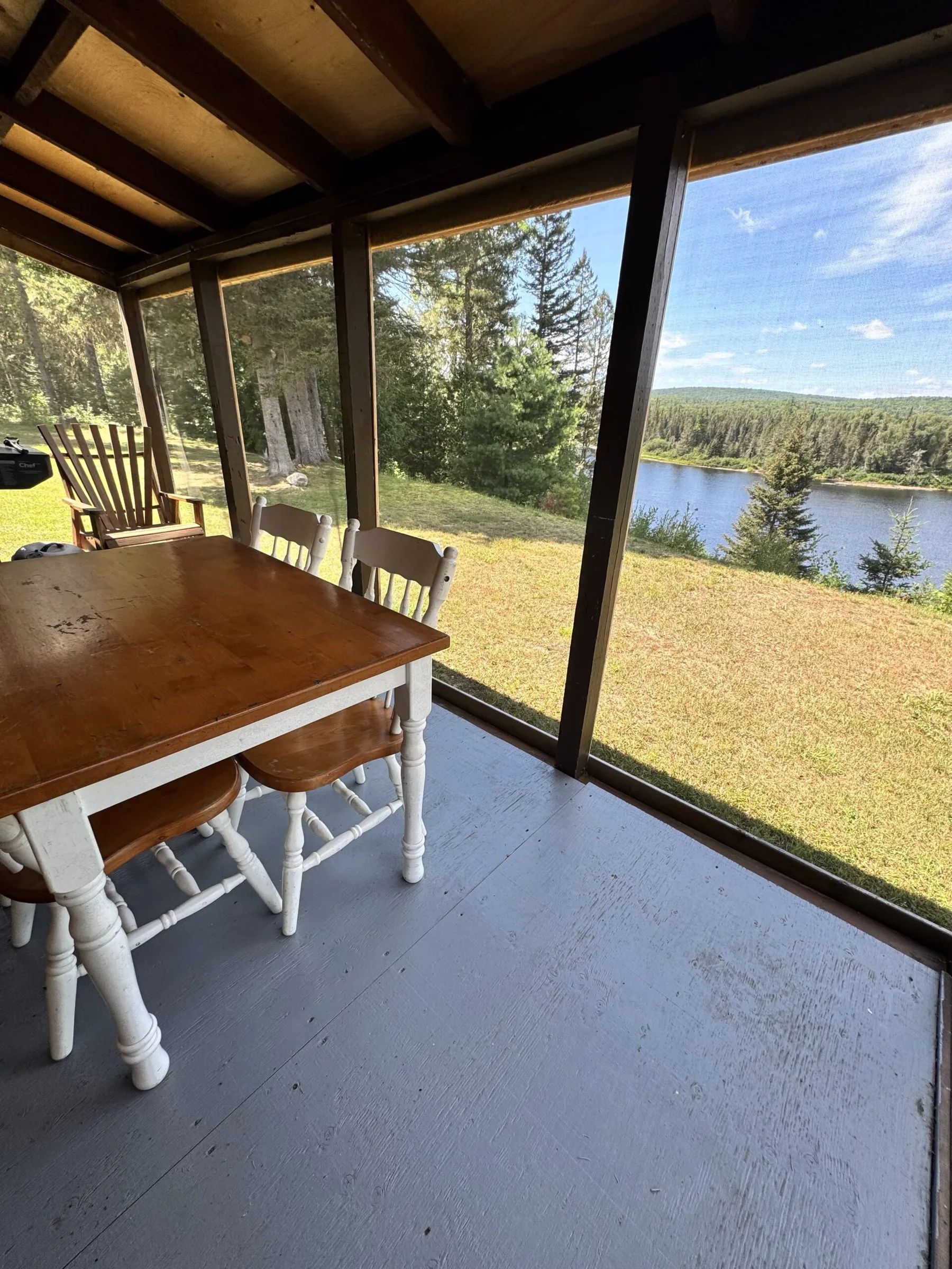 La véranda grillagée du chalet offre une vue imprenable sur le lac et la forêt environnante.
