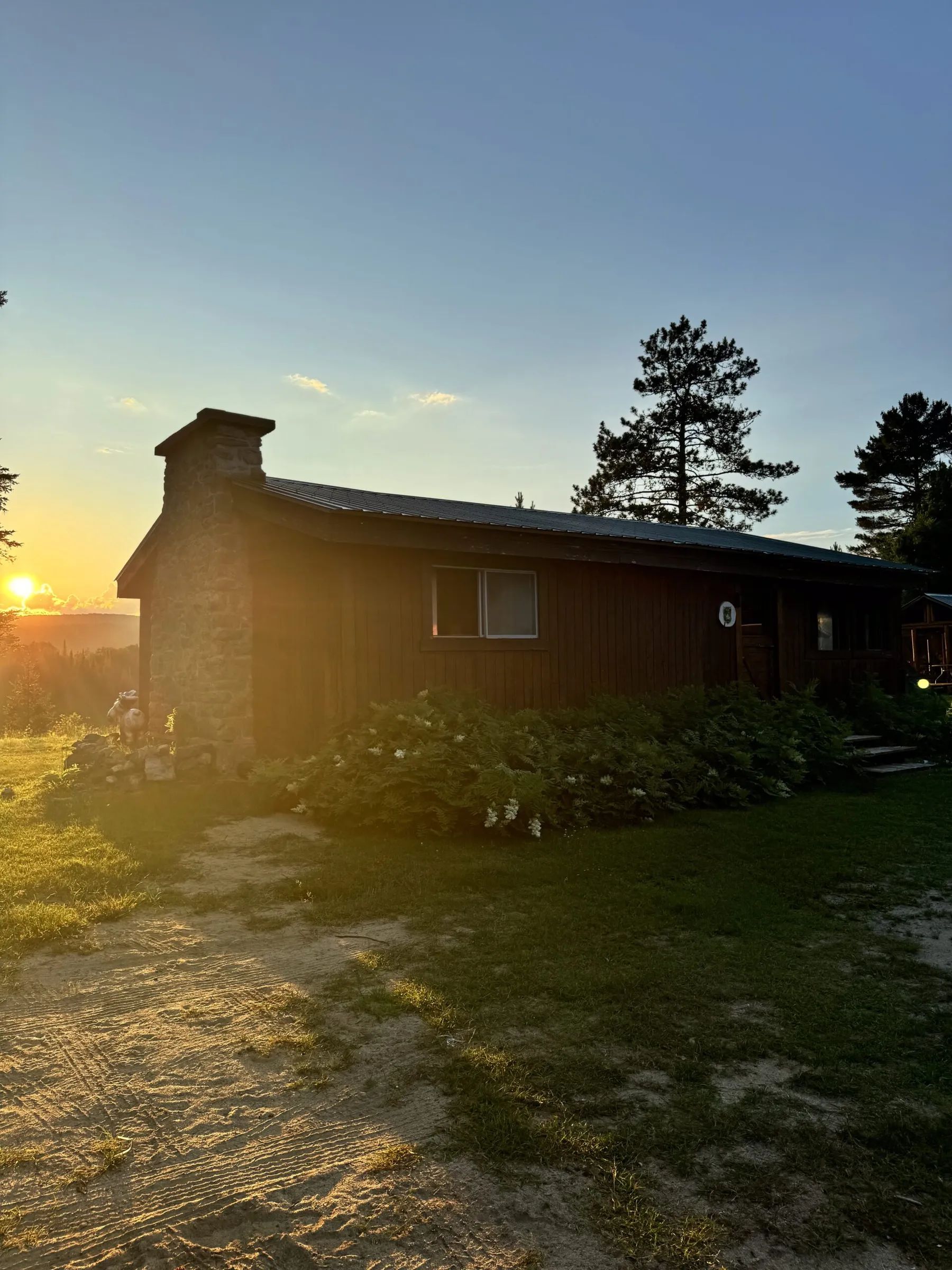 Le chalet L'Orignal au coucher du soleil avec sa cheminée en pierre.
