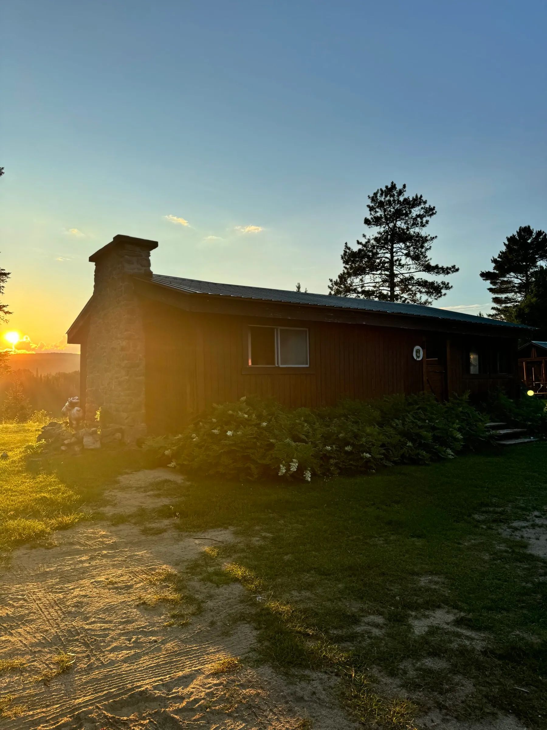Le chalet L'Orignal se dresse sous la lumière chaude du soleil couchant.