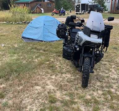 Vue sur le site de la pourvoirie avec chalet et espaces de camping pour les motocyclistes.