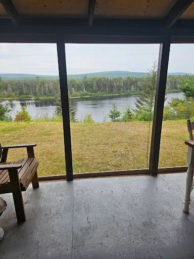 Vue imprenable sur la rivière et la forêt depuis la galerie couverte du chalet.