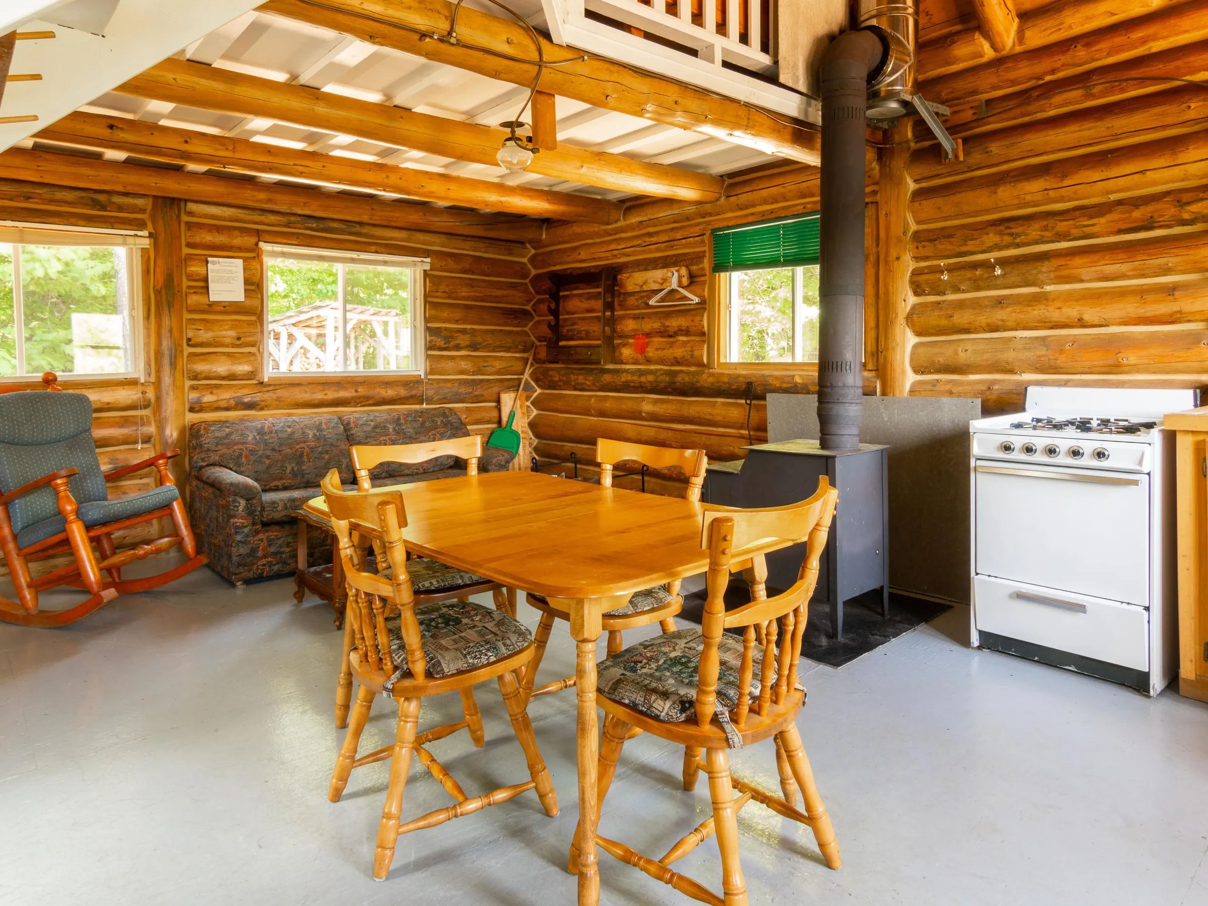Open living area featuring a dining table, a seating area, and a wood stove.