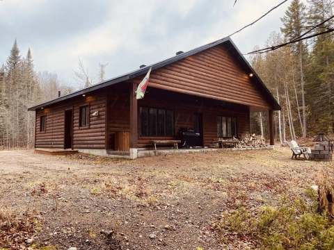 The Chalet des Loutres offers a rustic log space with a covered terrace and an outdoor fire pit.