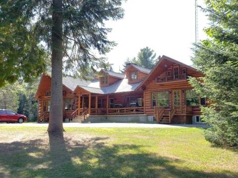 Overview of the log cabin surrounded by trees.
