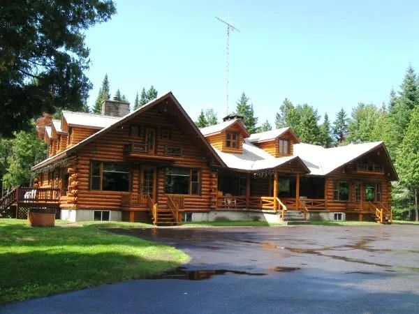 Exterior facade of the log cabin surrounded by the forest.