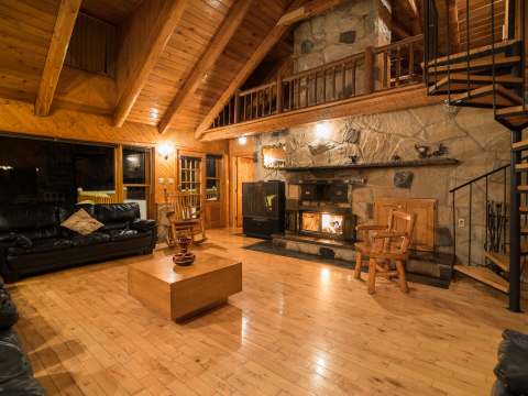 The chalet's cozy living room features a stone fireplace and a spiral staircase.