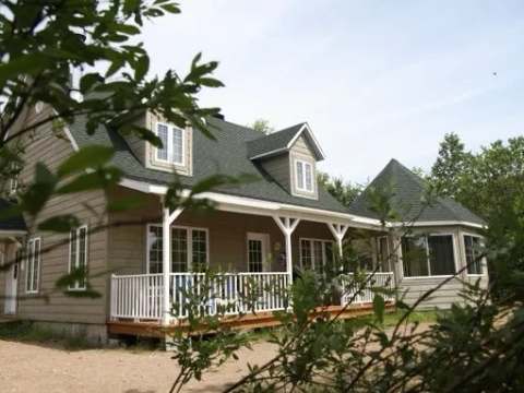 Exterior view of the spacious cottage with its covered porch and wooded surroundings.