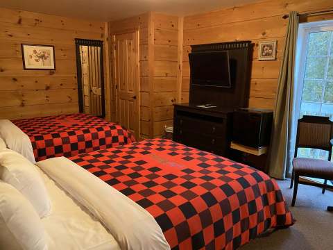 A rustic bedroom featuring two beds with red and black plaid bedspreads.