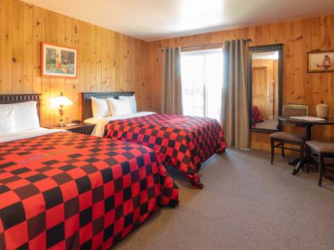 This rustic room features two beds with red and black checkered blankets.