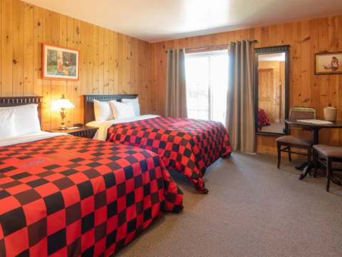 This rustic room features two double beds with red and black plaid bedspreads.