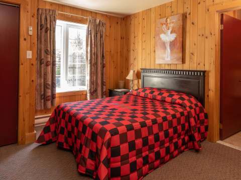 This classic room features a comfortable bed with red and black checkered bedding.