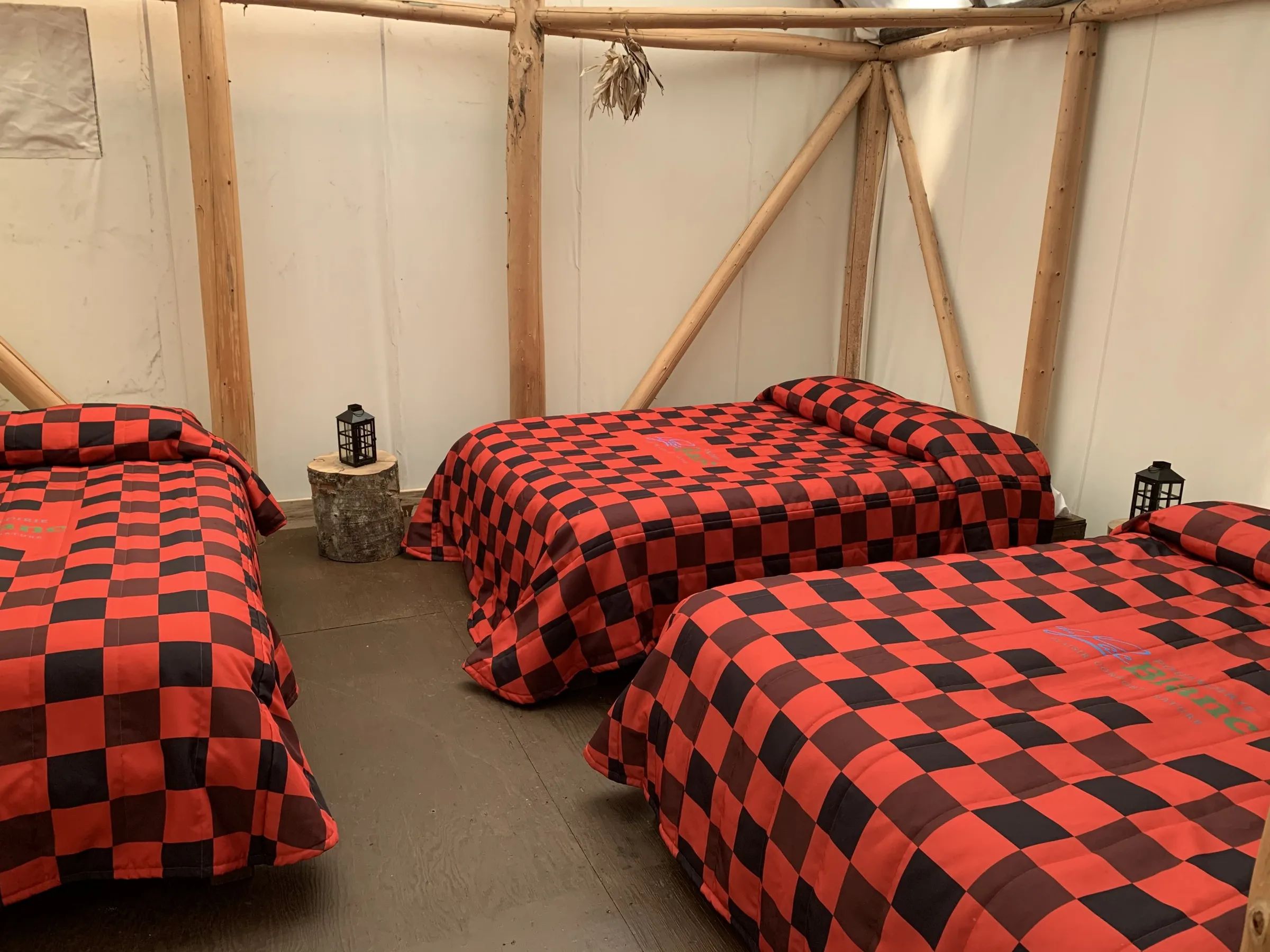 L'intérieur d'un prêt-à-camper aménagé avec des lits aux couvertures à carreaux rouges et noirs.