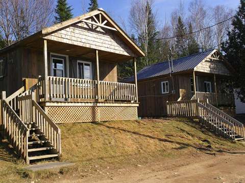 Vue extérieure des chalets en bois avec galerie et escaliers d'accès.