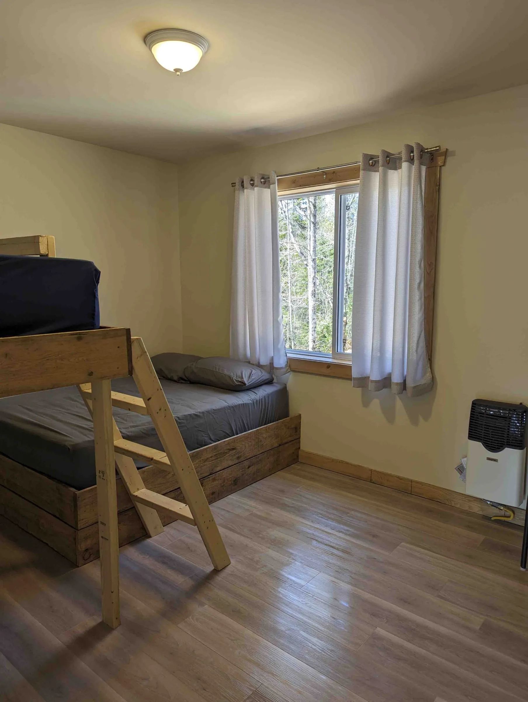 This bedroom at Chalet Canard features a bunk bed with a view of the forest.