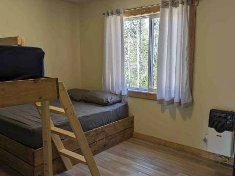 This bedroom at Chalet Canard features a bunk bed with a view of the forest.