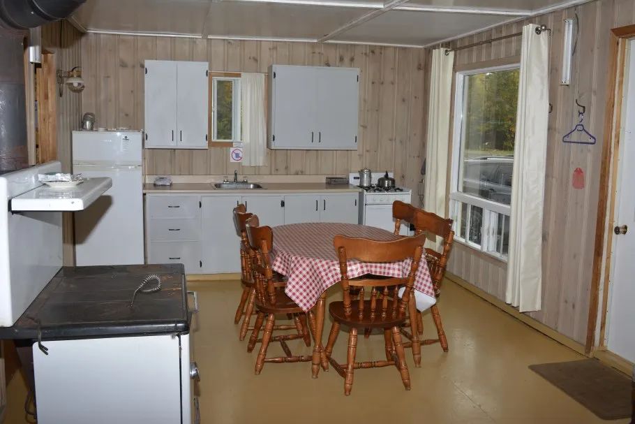 La cuisine fonctionnelle du chalet comprend une table à manger et des équipements de base.
