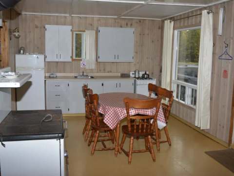 La cuisine fonctionnelle du chalet comprend une table à manger et des équipements de base.