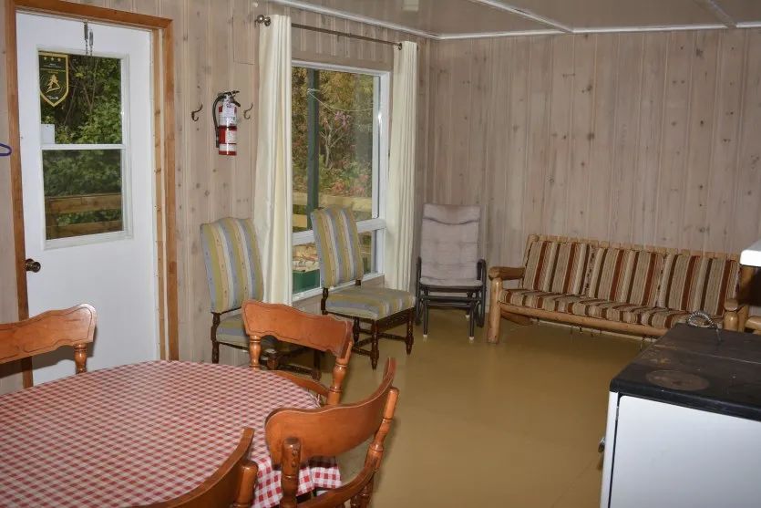 L'intérieur du chalet comprend une table à manger, des chaises et un coin salon avec canapé.