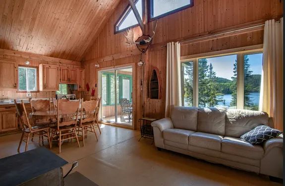 Vue sur l'aire ouverte et le coin repas du Chalet de l'Orignal avec sa fenestration donnant sur le lac.