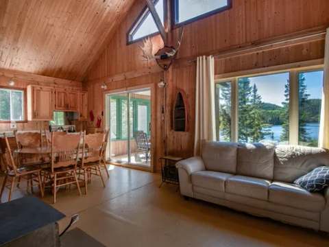 Vue sur l'aire ouverte et le coin repas du Chalet de l'Orignal avec sa fenestration donnant sur le lac.
