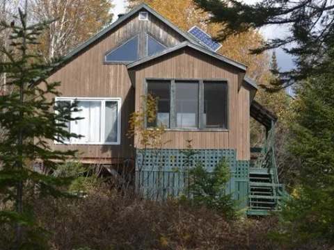 Le chalet de l'Orignal est un bâtiment en bois entouré par la forêt.