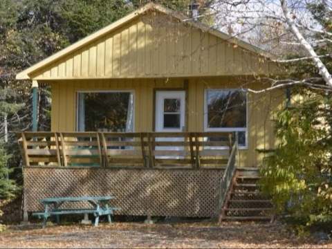 Vue de face du chalet de l'Orignal avec sa galerie et sa table de pique-nique.